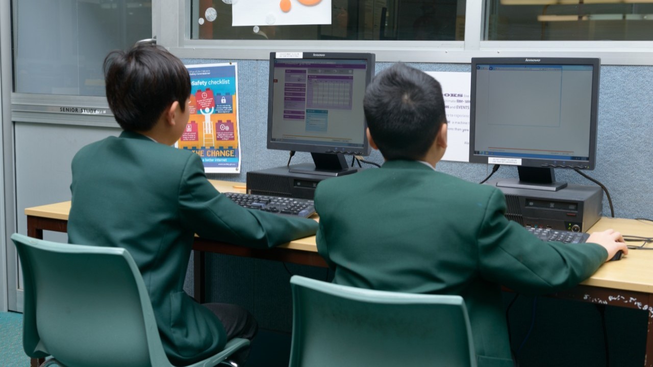 Two students working on desktops.